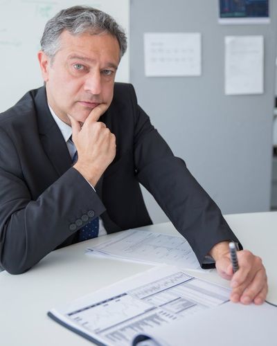 Experienced male analyst reviewing financial reports in professional environment